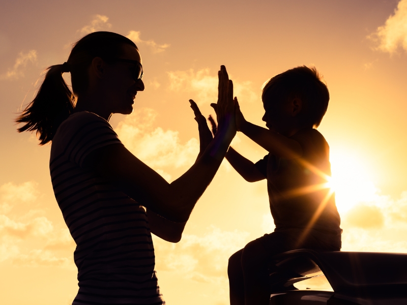 mother and child clapping hands at sunset